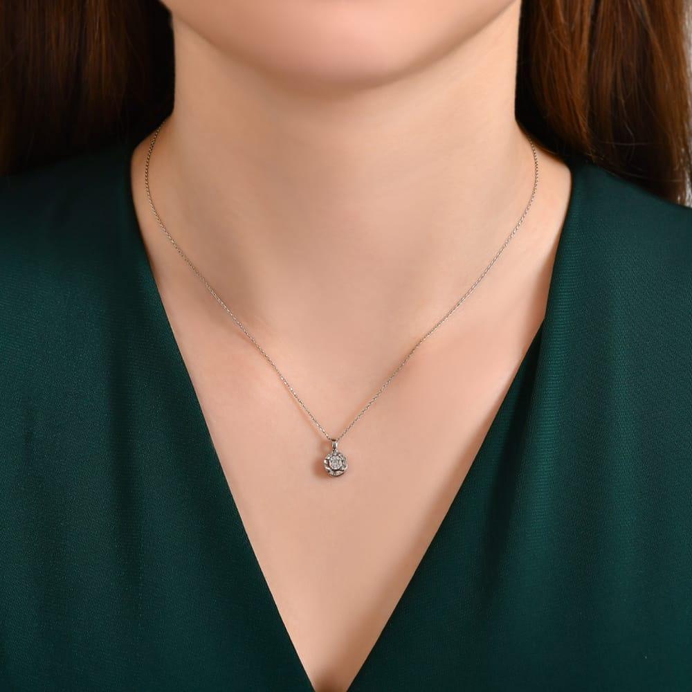 Woman wearing a silver diamond pendant necklace with green v-neck top