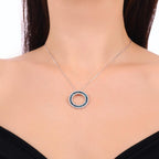 Silver necklace with circular sapphire and diamond pendant on woman's neck